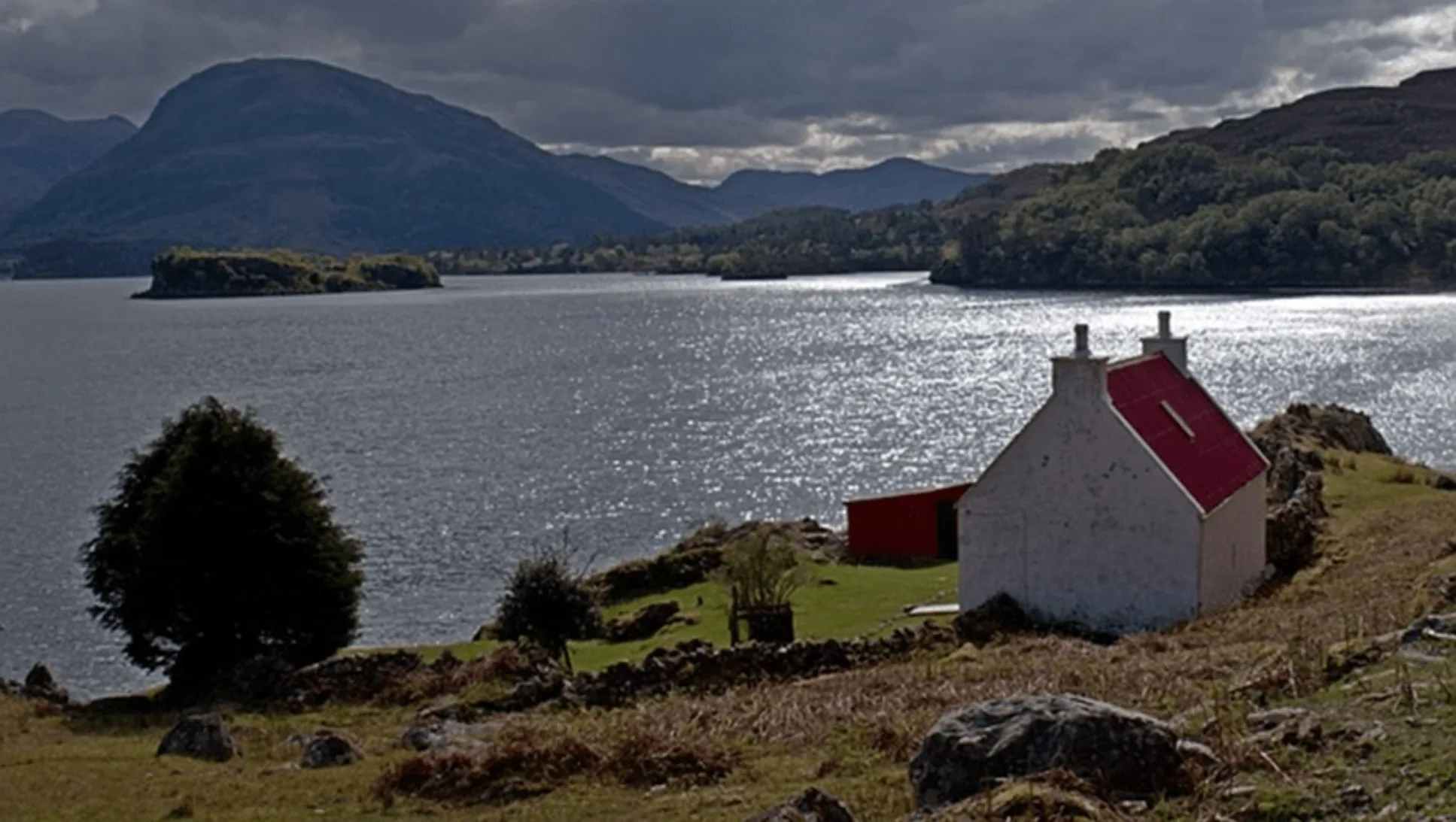 White house with red roof next to a lake