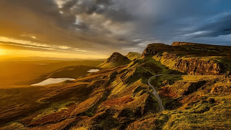 Road winding round mountains at sunset