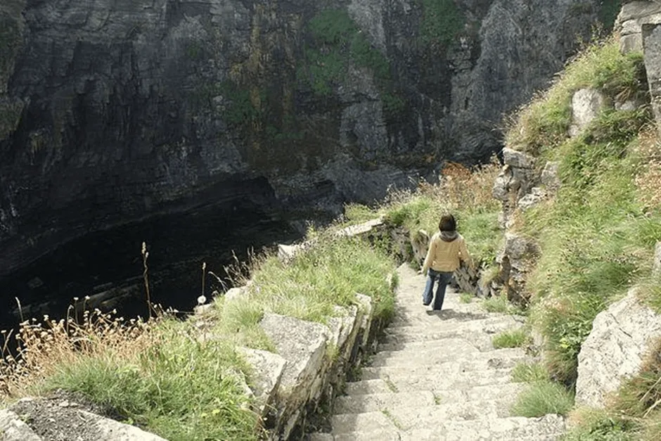 Woman walking down stone steps on a cliff