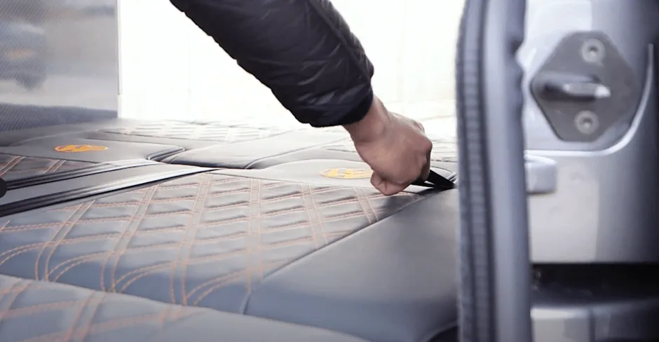 Person pulling a strap on VW camper van seat to fold it into a bed