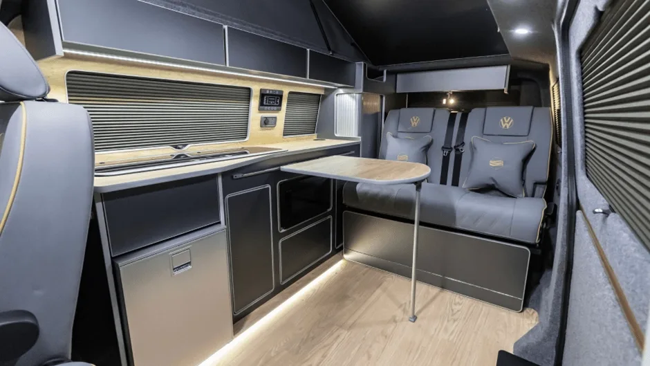 Full interior of VW campervan with wood floor and grey seats
