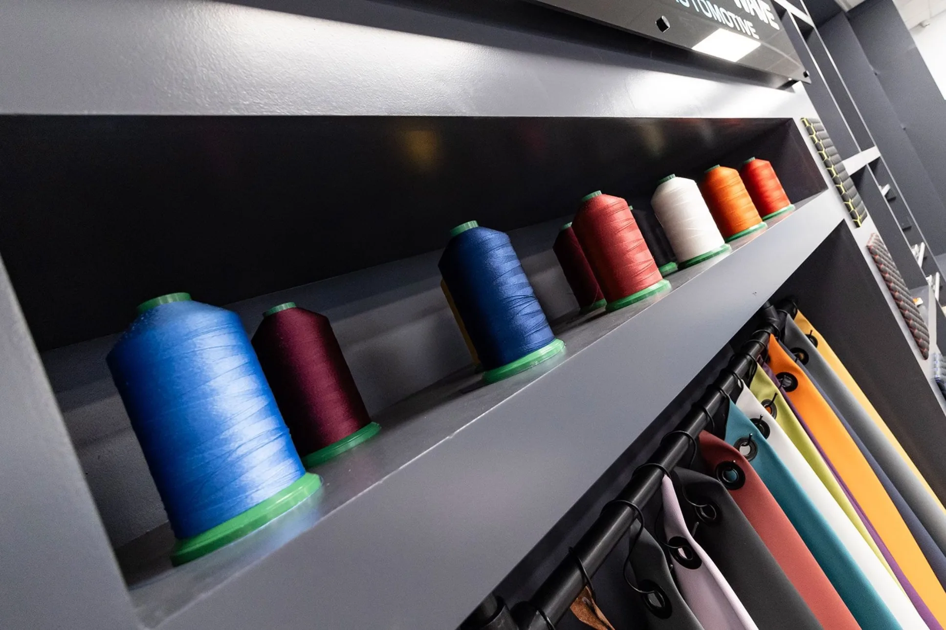 Brightly coloured thread spools on a grey shelf in Platinum Wave Automotive showroom