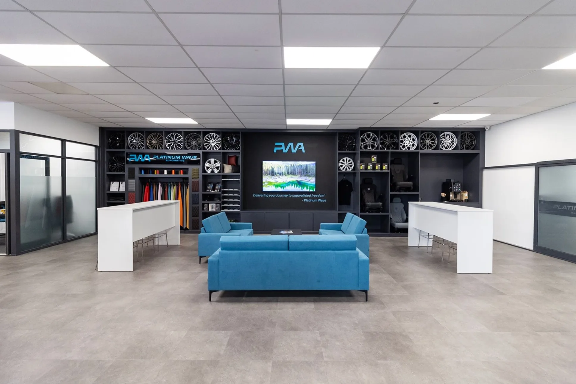 Platinum Wave Automotive show room with three blue sofas and a shelved wall