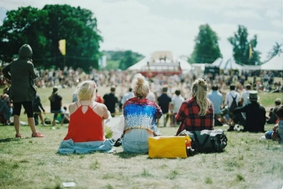 Three women sat at a festival in a crowd
