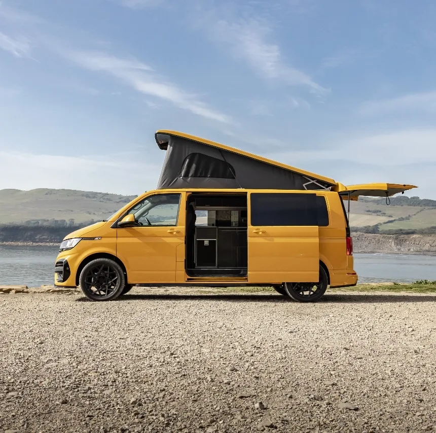 Yellow camper van with door and roof open on a beach