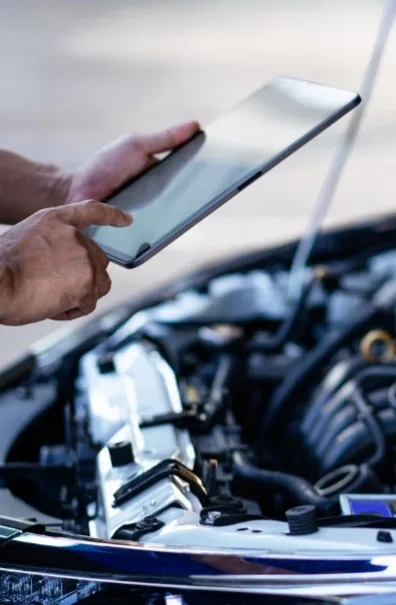 Mechanic using a tablet over an open van engine