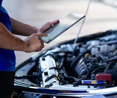 Mechanic using a tablet over an open van engine