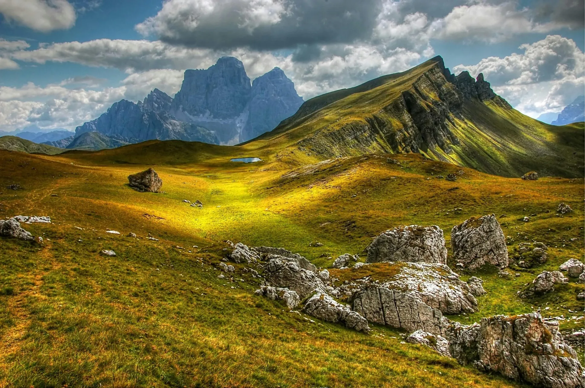Grassy path through mountains with moody skies