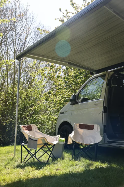 Chairs under an f45 awning attached to a campervan