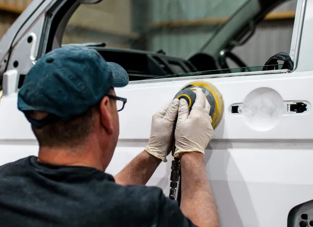 Platinum Wave Automotive employee buffing a white campervan